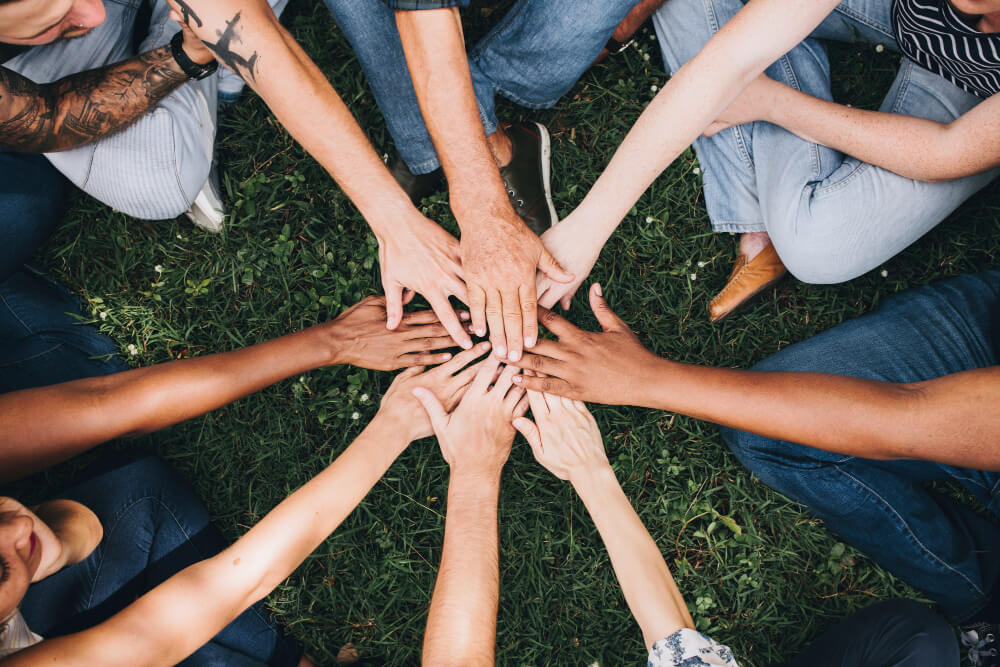 people stacking hands together park 