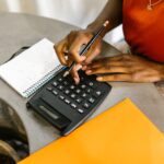 A person using a calculator and a notebook to calculate the hidden costs of homeownership